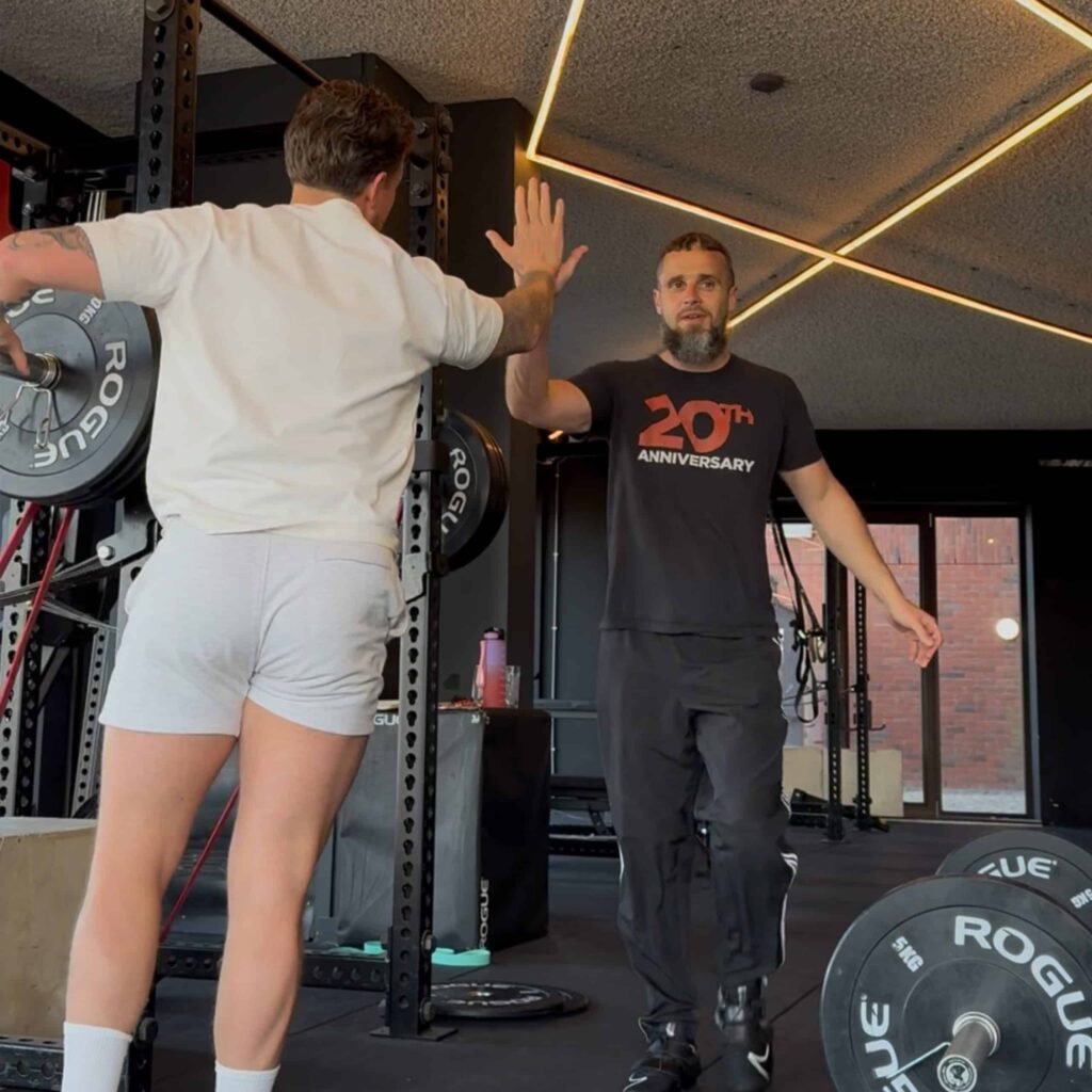 Coach high-five after a barbell set at Convoy Gym IJburg. Coach high-five after a barbell set at Convoy Gym IJburg.